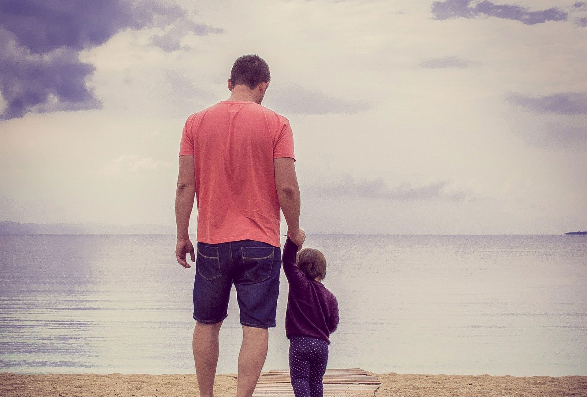 Vater mit Kind an der Hand am Wasser