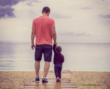 Vater mit Kind an der Hand am Wasser